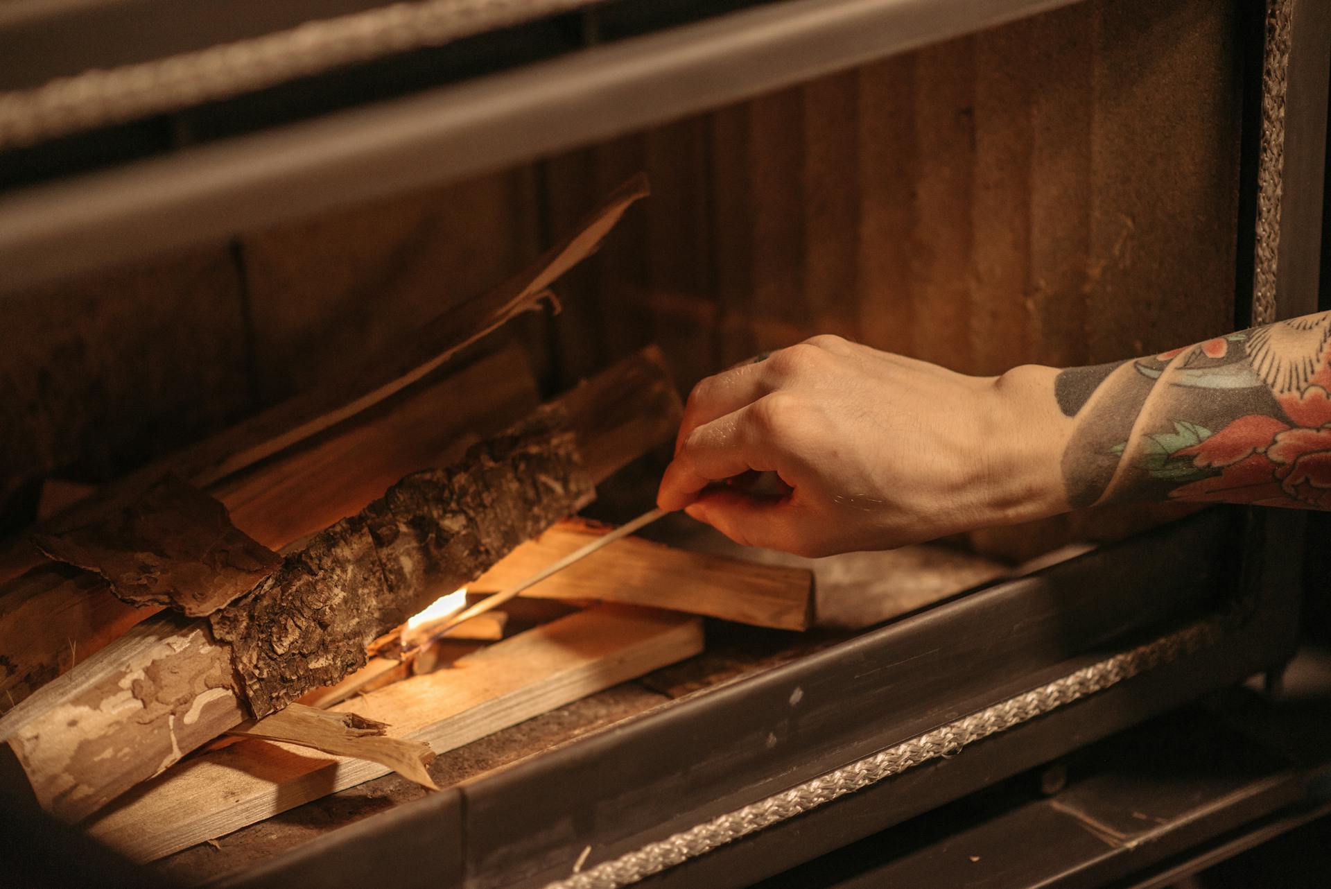 Aukšto efektyvumo plieninė krosnelė modernioje svetainėje su šilumą akumuliuojančia apdaila ir perdirbto kuro pavyzdžiais.